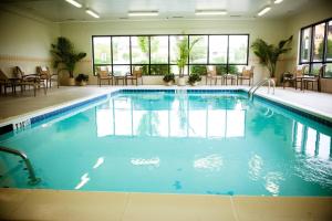 a large swimming pool in a hotel with tables and chairs at Chester Inn & Suites in Sharonville