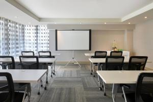 une salle de classe avec des tables et des chaises et un écran de projection dans l'établissement Four Points by Sheraton Coral Gables, à Miami