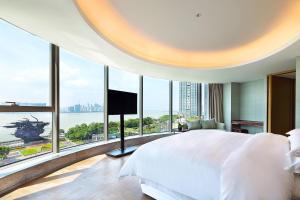 a bedroom with a large bed and large windows at Sheraton Grand Hangzhou Binjiang Hotel in Hangzhou