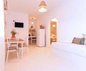 a white living room with a table and a refrigerator at La Vista TINOS in Agios Ioannis