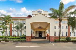 un bâtiment avec des palmiers en face de celui-ci dans l'établissement Protea Hotel by Marriott Blantyre Ryalls, à Blantyre