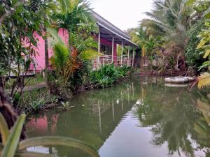 una casa junto a un cuerpo de agua con árboles en Ban Suan Lung Rin en Kanchanaburi