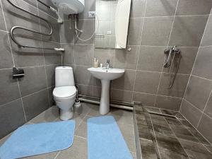 ein Badezimmer mit einem WC und einem Waschbecken mit blauen Matten in der Unterkunft 14-38 вид на море лучший район in Aqtau