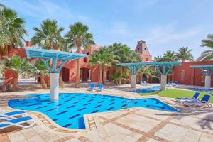 a pool at a resort with blue chairs and palm trees at Sheraton Miramar Resort El Gouna in Hurghada