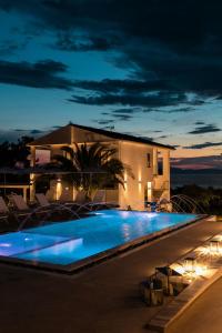 a swimming pool in front of a house at night at Pachis Escape Suites in Pachis