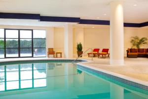 a swimming pool in a hotel with red chairs and tables at The Westin Waltham Boston in Waltham