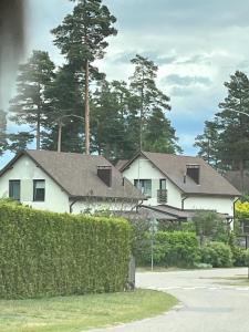 una casa blanca con un seto delante de ella en Casa del bosque, en Upesciems
