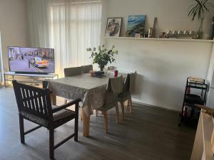 comedor con mesa con sillas y TV en Casa del bosque, en Upesciems