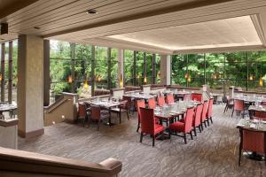 um restaurante com mesas, cadeiras vermelhas e janelas em Sheraton Suites Akron Cuyahoga Falls em Cuyahoga Falls