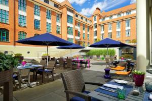 an outdoor patio with tables and chairs and umbrellas at Sheraton Hannover Pelikan Hotel in Hannover