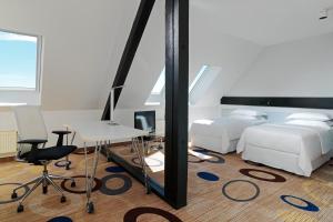 a bedroom with a bed and a desk and a mirror at Sheraton Hannover Pelikan Hotel in Hannover