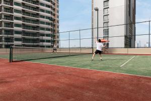 two people playing tennis on a tennis court at Marriott Executive Apartments Sukhumvit Park, Bangkok in Bangkok