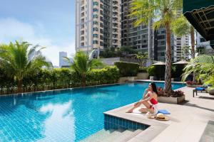 una mujer en bikini rojo sentada junto a una piscina en Marriott Executive Apartments - Sukhumvit Park, Bangkok, en Bangkok