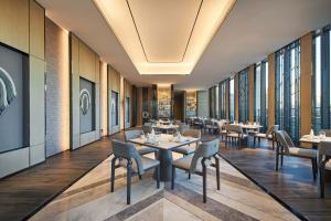 um restaurante com mesas, cadeiras e janelas em Courtyard by Marriott Changchun em Changchun