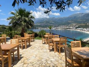 una fila de mesas y sillas con vistas al agua en Hotel Mesun Himare, en Himare