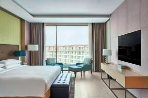 a hotel room with a bed and a large window at Marriott Jeju Shinhwa World Hotel in Seogwipo