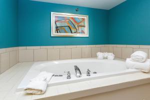 Fairfield Inn & Suites Des Moines West في ويست دي موينز: حمام مع حوض استحمام مع لوحة على الحائط