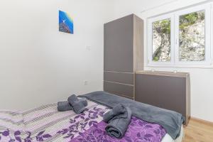 a bedroom with a bed with purple sheets and two windows at Stunning apartment in quiet street near center With free parking 4 floor in Rijeka