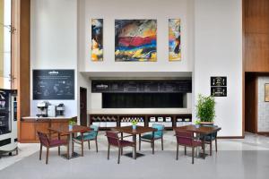 a dining room with tables and chairs and paintings on the wall at Four Points by Sheraton Navi Mumbai, Vashi in Navi Mumbai