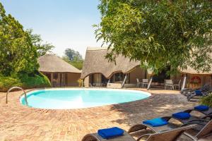 a swimming pool with lounge chairs and a resort at Protea Hotel by Marriott Oudtshoorn Riempie Estate in Oudtshoorn