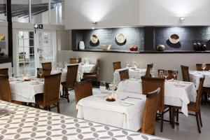 Protea Hotel by Marriott Oudtshoorn Riempie Estate في أوتشورن: مطعم بطاولات وكراسي مع طاولة قماش بيضاء