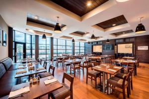 a restaurant with wooden tables and chairs and windows at Four Points By Sheraton Houston Energy Corridor in Katy