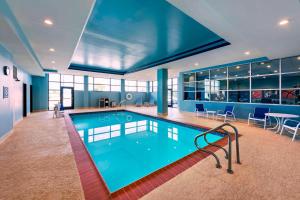 a large swimming pool in a building with tables and chairs at Four Points By Sheraton Houston Energy Corridor in Katy