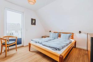 a bedroom with a bed and a chair and a window at Zur Oie 27 in Bresewitz