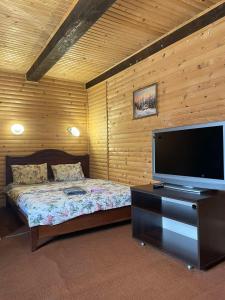um quarto com uma cama e uma televisão de ecrã plano em Котедж em Vorokhta