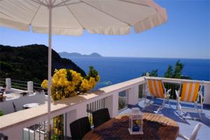 einen Balkon mit einem Sonnenschirm, einem Tisch und Stühlen in der Unterkunft Ponza Vista Mare in Ponza