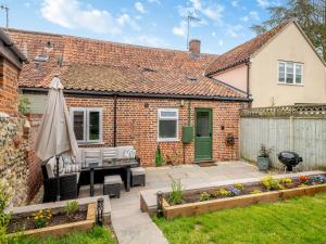 a garden with a patio and an umbrella at Seascape Cottage in South Creake