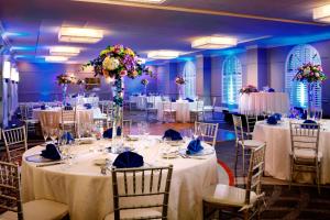um salão de banquetes com mesas e toalhas de mesa brancas em Sheraton Suites Fort Lauderdale at Cypress Creek em Fort Lauderdale