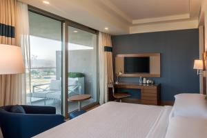 a hotel room with a bed and a desk and a tv at Four Points by Sheraton Izmir in İzmir
