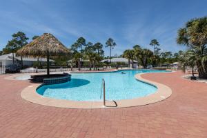 a large swimming pool with a straw umbrella at Beach House steps to pool, Beach Access in Gulf Shores