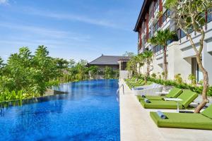 a pool at a hotel with green lounge chairs at Renaissance Bali Nusa Dua Resort in Nusa Dua