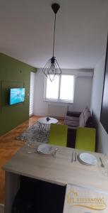 a living room with a table and green chairs at Apartman Stevanovic BN in Bijeljina