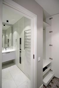 a white bathroom with a shower and a sink at Новые великолепные апартаменты в центре, Желтоксан 159 in Almaty