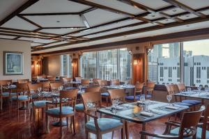 a restaurant with tables and chairs and large windows at Le Meridien Makkah in Mecca