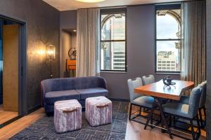 a living room with a couch and a table and chairs at The Industrialist Hotel, Pittsburgh, Autograph Collection in Pittsburgh