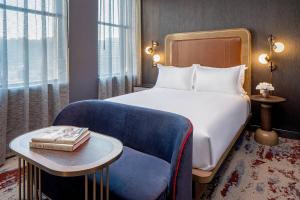 une chambre d'hôtel avec un lit et une chaise bleue dans l'établissement The Industrialist Hotel, Pittsburgh, Autograph Collection, à Pittsburgh