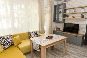 salon z żółtą kanapą i telewizorem w obiekcie Alagen Apartments Burgas w Burgas