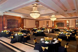 a banquet hall with black tables and chairs and chandeliers at Sheraton New Delhi Hotel in New Delhi