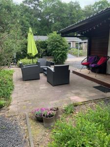 un patio con sillas, sombrilla y flores en Sfeervolle blokhut op de Veluwe op recreatiepark Topparken in Beekbergen met vrije tuin en eigen parkeerplaats, en Beekbergen