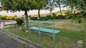 a blue bench sitting in the grass next to a tree at Rocca di Luna a Gemmano in Gemmano