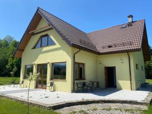 a yellow house with a table and chairs at Domki u Ewy in Stronie Śląskie
