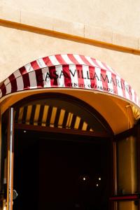 Sella&Mosca Casa Villamarina في ألغيرو: شمسية حمراء وبيضاء فوق باب المبنى