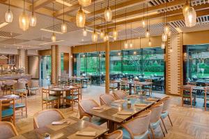 a restaurant with wooden tables and chairs and windows at Sheraton Shanghai Chongming Hotel in Chongming