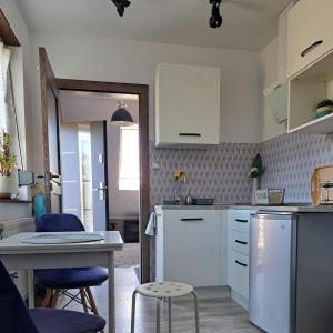 a kitchen with white cabinets and a table and chairs at Mały Apartamencik Teo in Rewal