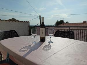 a bottle of wine and two wine glasses on a table at Sonja Apartment in Premantura