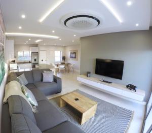 a living room with a couch and a tv at Stylish Sea View Apartment in Santorini Estate. in Ballito